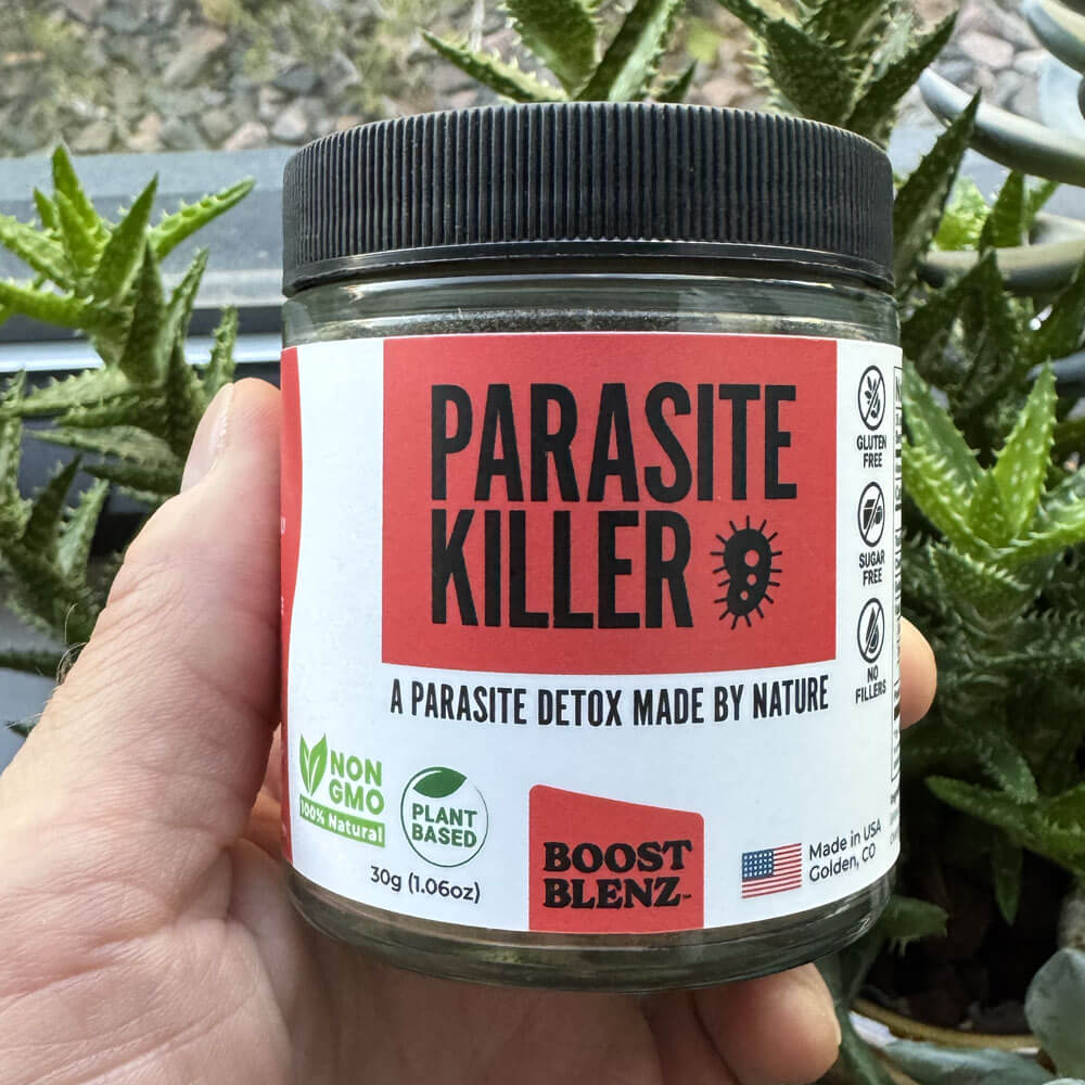 Jar labeled 'Parasite Killer' held by a hand with plants in the background